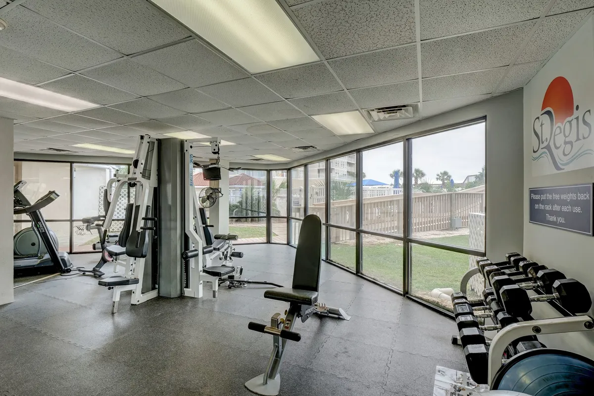 A modern, spacious fitness center filled with exercise machines, free weights, and large windows allowing natural light to pour in. The area has an energetic atmosphere, ideal for workouts or post-work relaxation, and even features a sauna for rejuvenation.