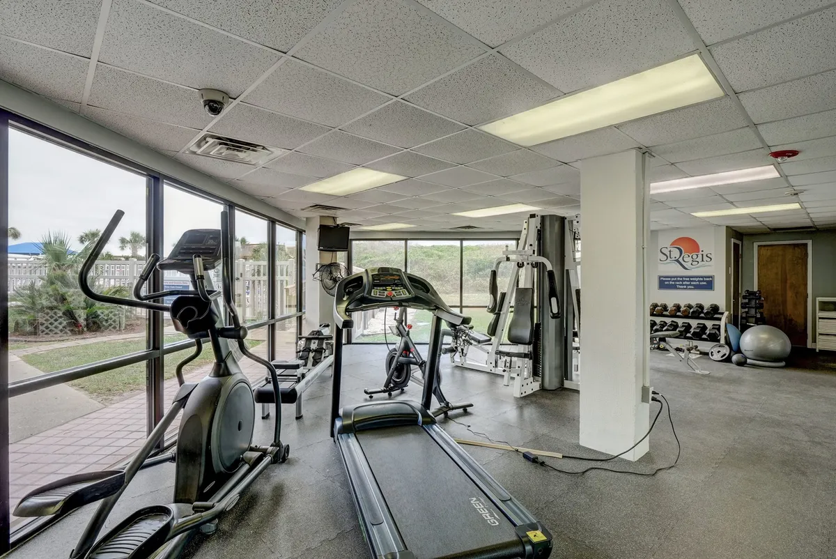 A bright and energetic fitness center featuring treadmills, elliptical machines, weight machines, and expansive windows allowing in plenty of natural light. The modern equipment and spacious layout invite guests to stay active and healthy.