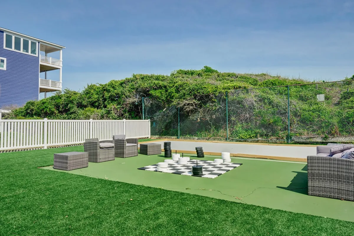 This image shows a large outdoor chess set surrounded by comfortable seating and lush greenery. Groups of people are seen playing chess, socializing, and relaxing in the inviting outdoor space. The ambiance is playful and relaxed, perfectly capturing the spirit of friendly gatherings and outdoor fun.